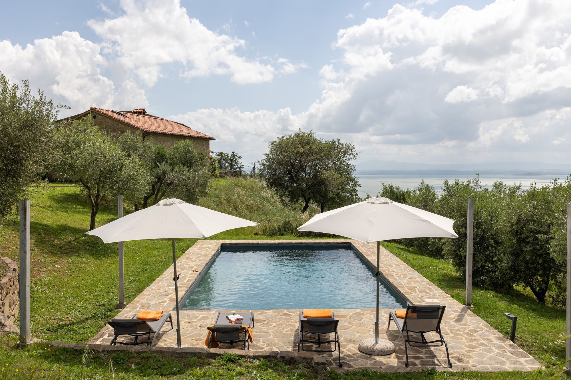 Pool terrace with parasols and a view towards Lake Trasimeno